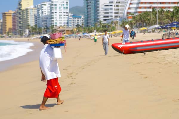 Condesa Beach featuring a coastal town and a beach as well as an individual male