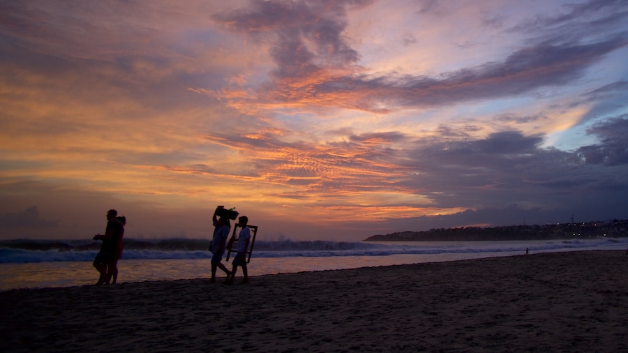 Puerto Escondido featuring a sunset and a sandy beach as well as a small group of people