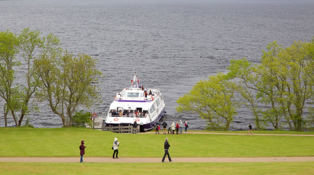 Lago Ness que incluye vista general a la costa y un ferry y también un pequeño grupo de personas