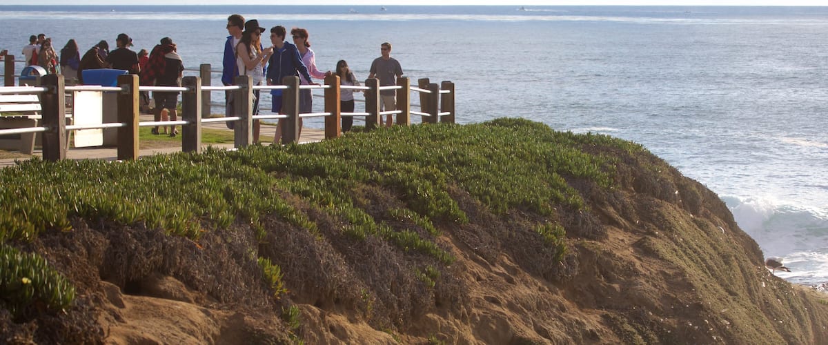 La Jolla Cove which includes rugged coastline and general coastal views as well as a small group of people