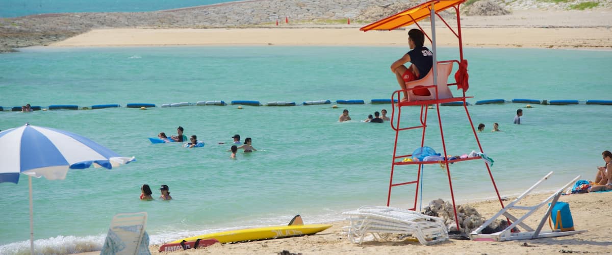 Okinawa som inkluderar en sandstrand och bad såväl som en stor grupp av människor