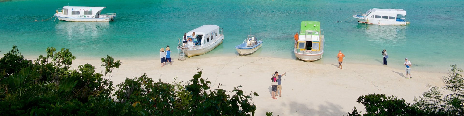 Kabira Bay Beach showing a sandy beach and boating as well as a small group of people