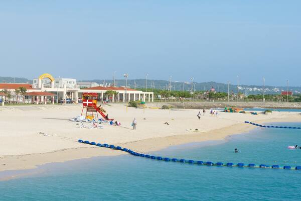 Okinawa montrant ville cĂŽtiĂšre, plage de sable et baignade