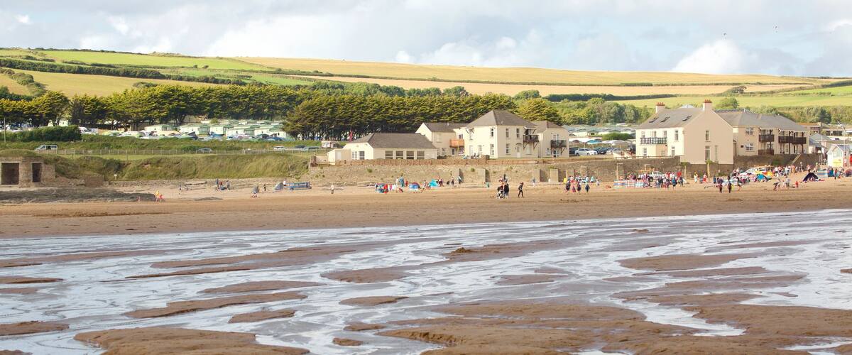 Croyde featuring hiekkaranta ja rannikkokaupunki sekä suuri ryhmä ihmisiä