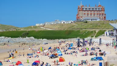 Fistral Beach som visar en strand och en kuststad såväl som en stor grupp av människor