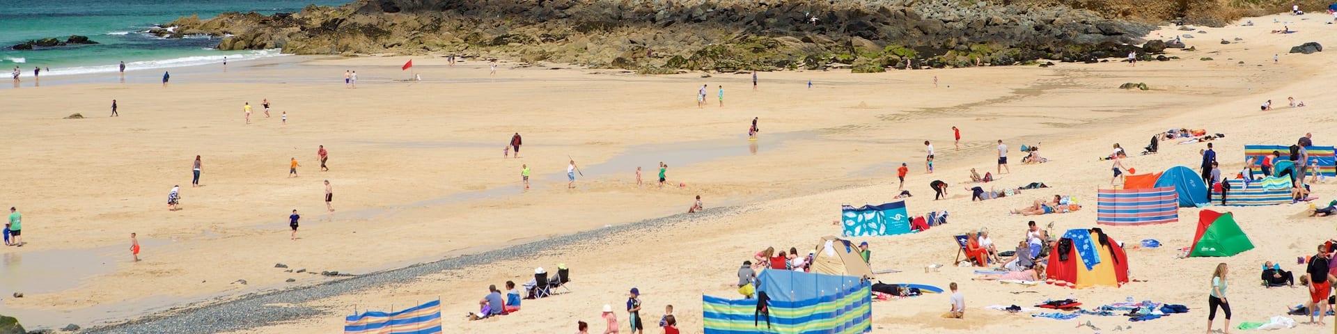 Porthmeor Beach featuring a coastal town and a sandy beach as well as a large group of people