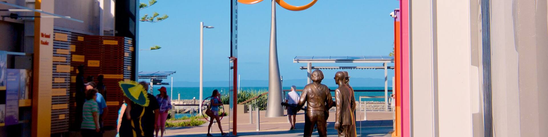 Bee Gees Way featuring general coastal views and outdoor art as well as a small group of people