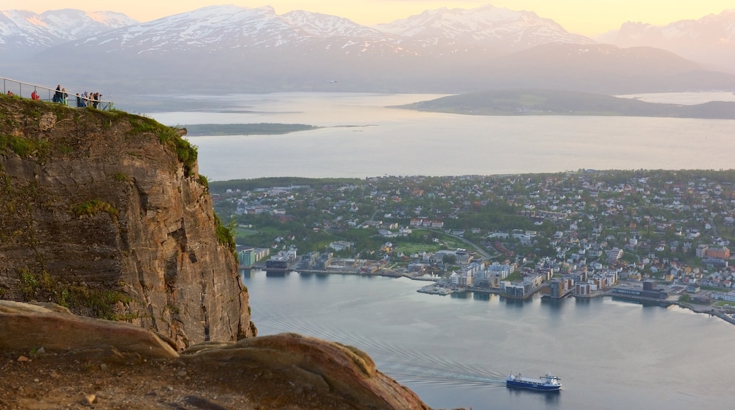 Tromsö som inkluderar en solnedgång, en liten stad eller by och berg