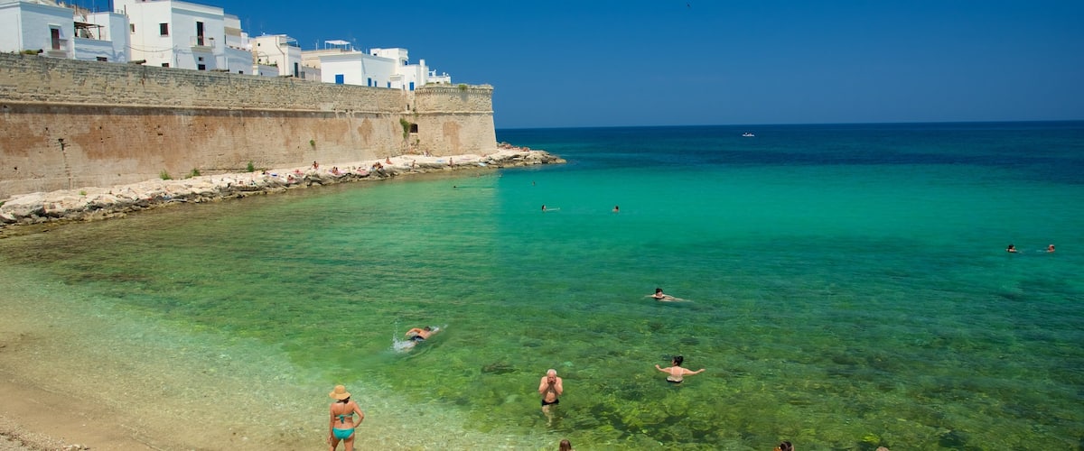 Monopoli mostrando una playa de guijarros y costa rocosa y también un gran grupo de personas