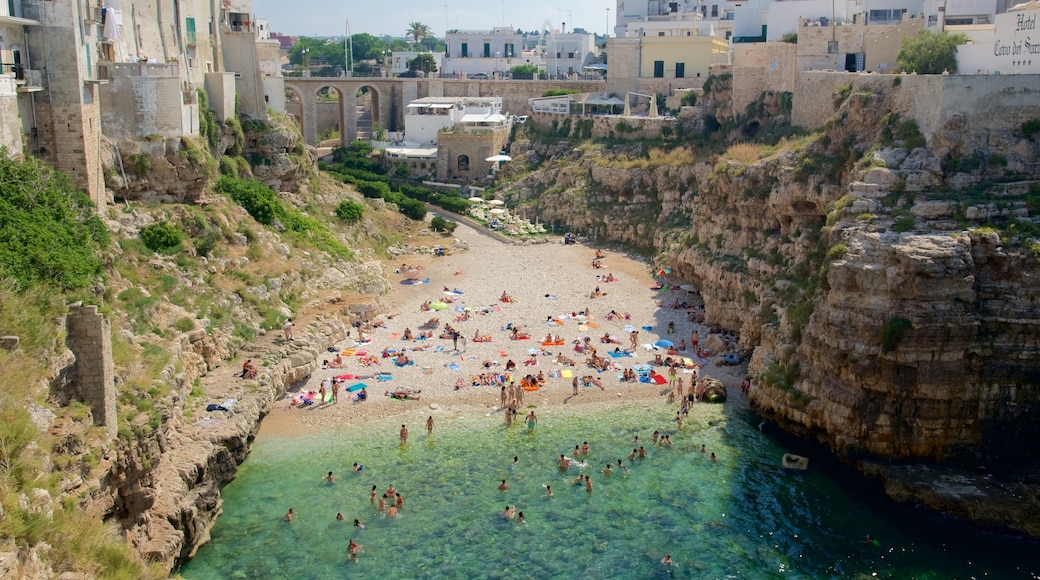 Polignano a Mare which includes a sandy beach and rocky coastline as well as a large group of people