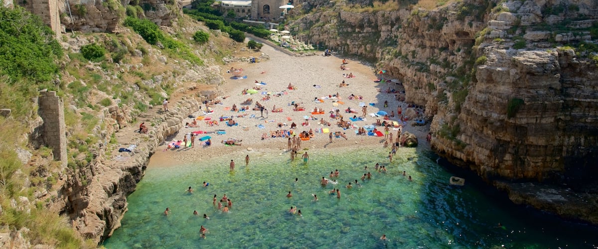 Polignano a Mare which includes a sandy beach and rocky coastline as well as a large group of people