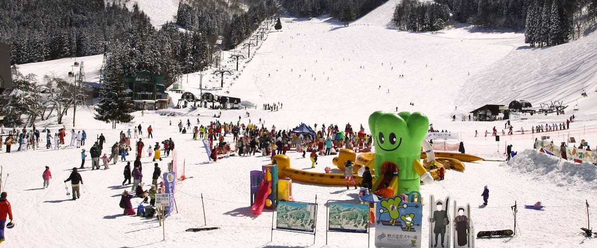 Estación de esquí de Nozawa Onsen mostrando nieve y un hotel o resort de lujo y también un gran grupo de personas