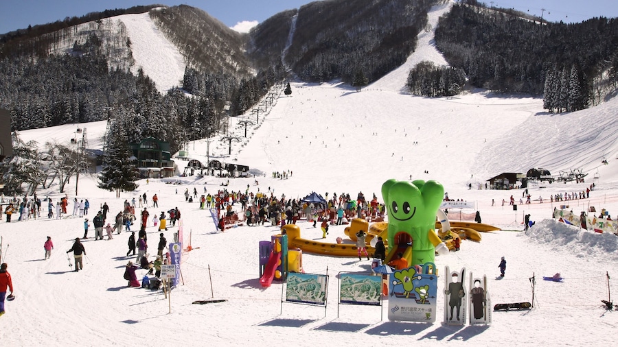 Estación de esquí de Nozawa Onsen mostrando nieve y un hotel o resort de lujo y también un gran grupo de personas