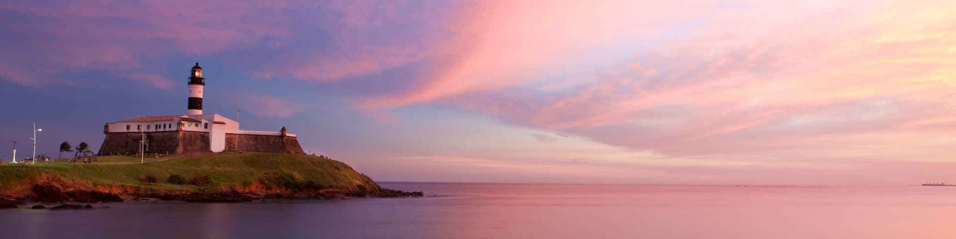 Farol da Barra Beach featuring a lighthouse, a sunset and general coastal views