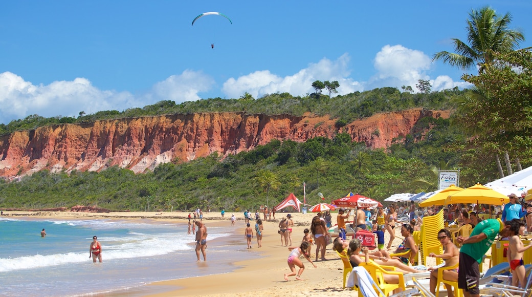 Praia da Pitinga welches beinhaltet Strand und allgemeine Küstenansicht sowie große Menschengruppe