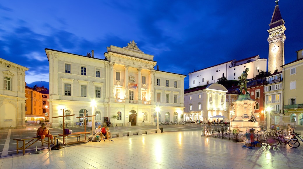 Piran mostrando una estatua o escultura, escenas nocturnas y una plaza