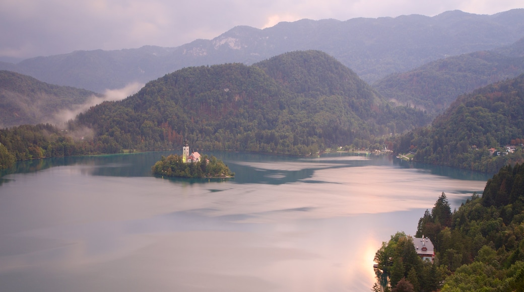 Lago de Bled mostrando niebla, montañas y un lago o laguna