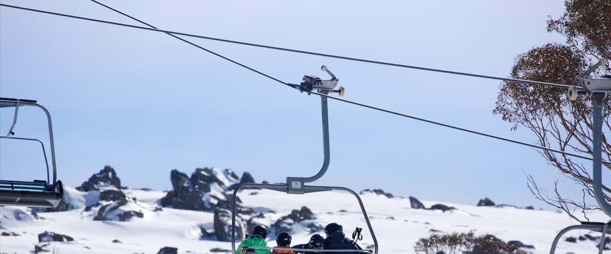 Snowy Mountains featuring a gondola and mountains as well as a family