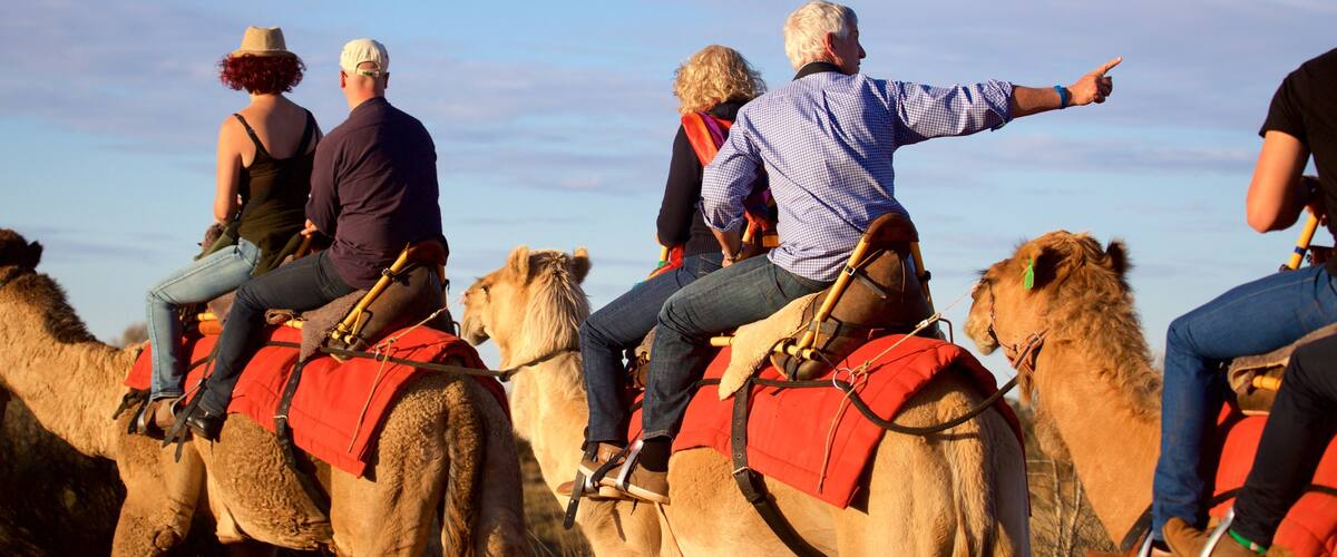 Uluru which includes desert views and horse riding as well as a small group of people