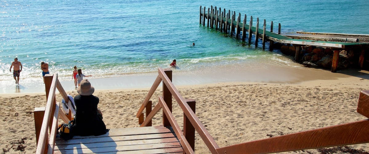 Prevelly Beach which includes a sandy beach and a bay or harbour as well as a small group of people