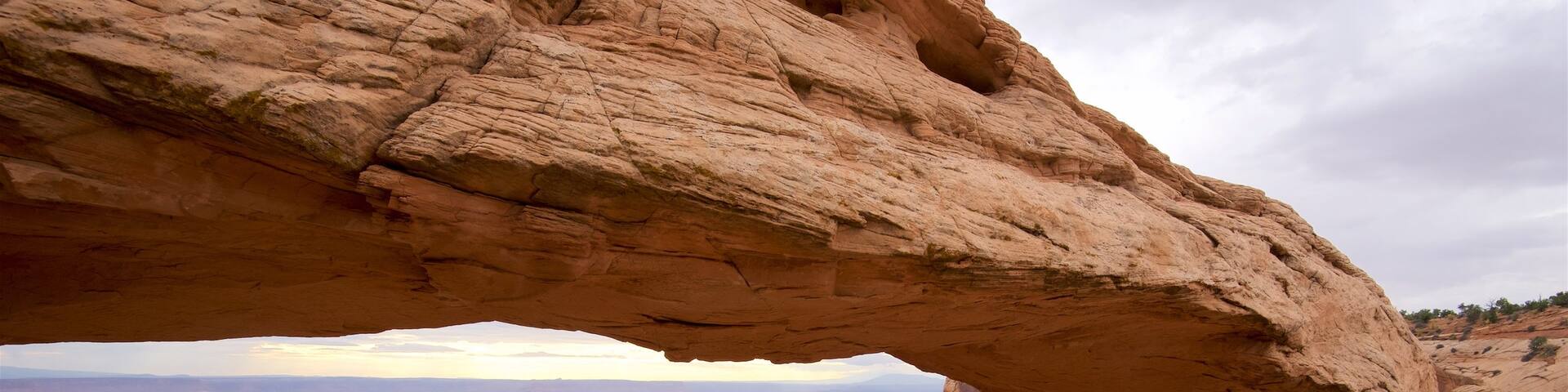 Mesa Arch Trail featuring a gorge or canyon, mountains and tranquil scenes