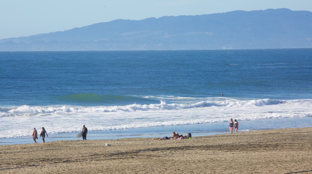 Ocean Beach showing a sandy beach and surfing as well as a small group of people