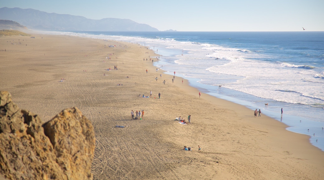 Ocean Beach featuring landscape views and a sandy beach as well as a large group of people