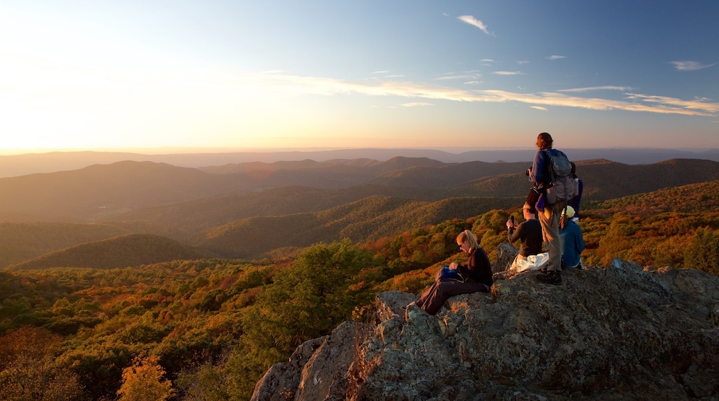 Shenandoah National Park featuring a sunset and mountains as well as a small group of people