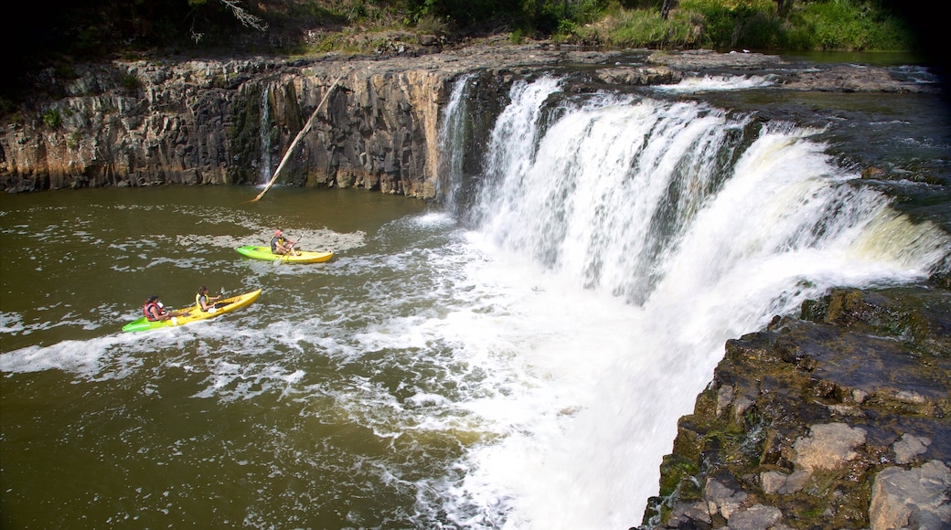 Haruru Falls toont kajakken of kanoën, een waterval en een rivier of beek