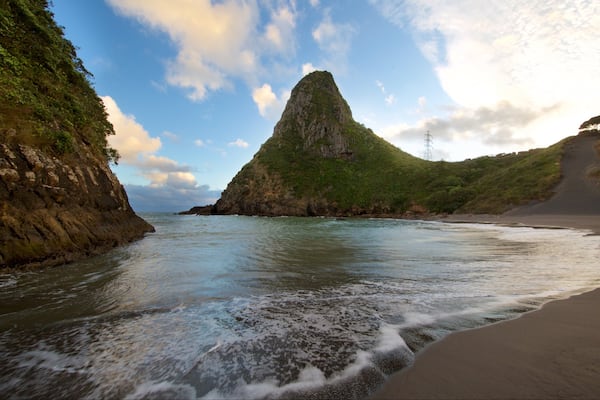 Paritutu Rock featuring a sunset, a bay or harbour and a sandy beach