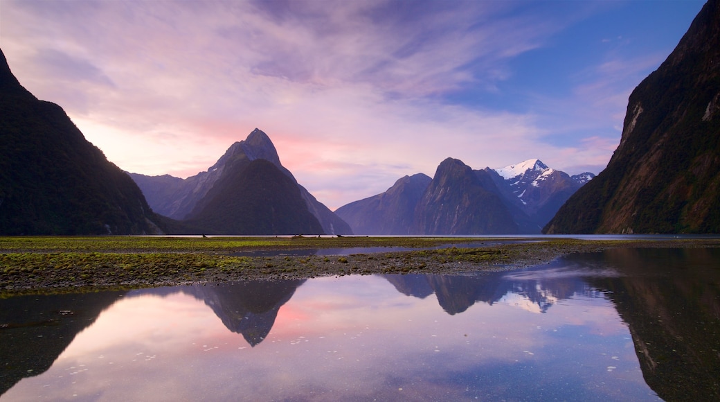 Milford Sound som inkluderar en sjö eller ett vattenhål, berg och en solnedgång