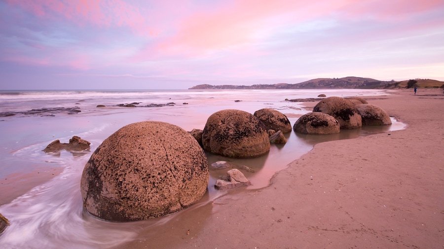 Moeraki Boulders ofreciendo un atardecer, una playa y litoral accidentado