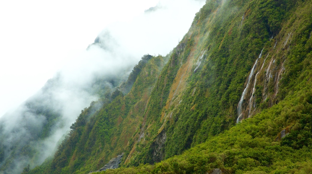 Fox Glacier featuring mountains, mist or fog and a cascade