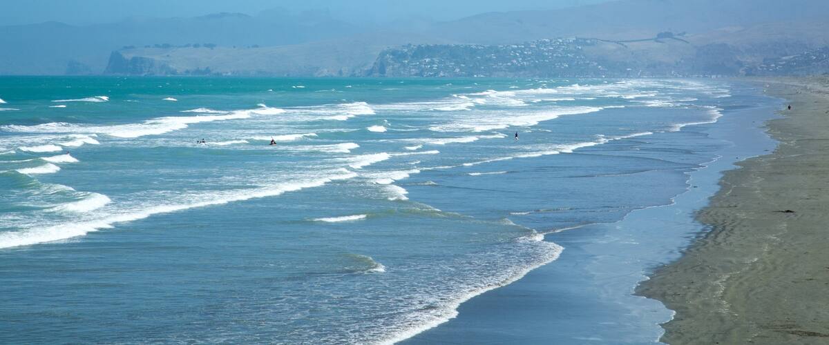 New Brighton Beach showing surfing, a beach and a coastal town