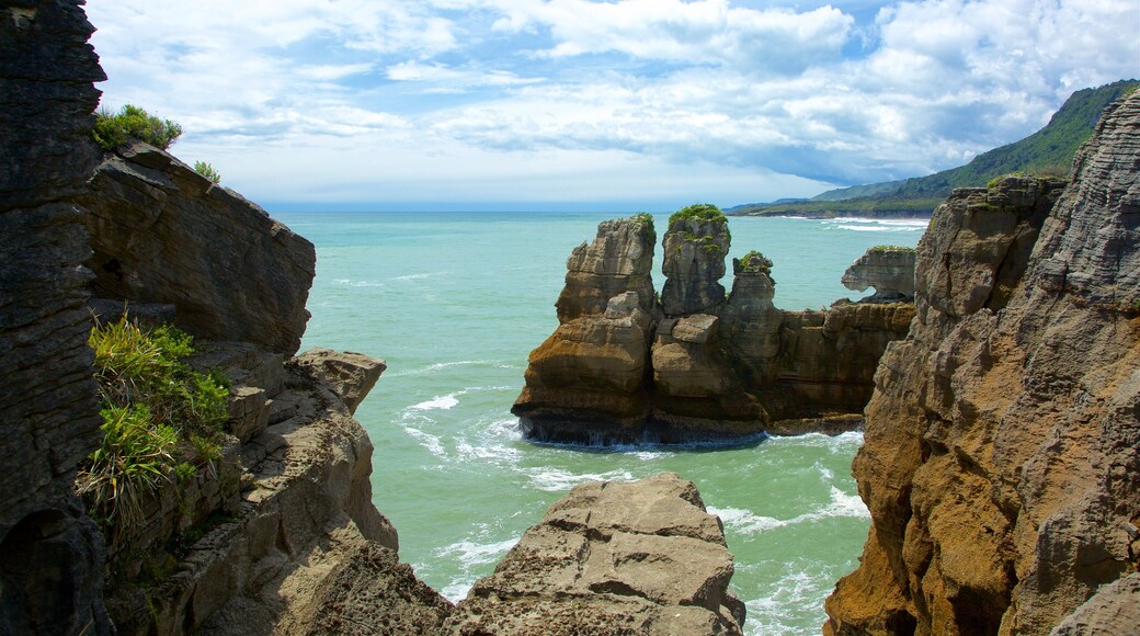 Pancake Rocks inclusief bergen, een baai of haven en rotsachtige kustlijn