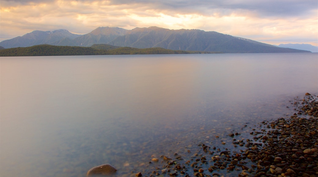 Lake Te Anau presenterar berg, en solnedgång och en sjö eller ett vattenhål