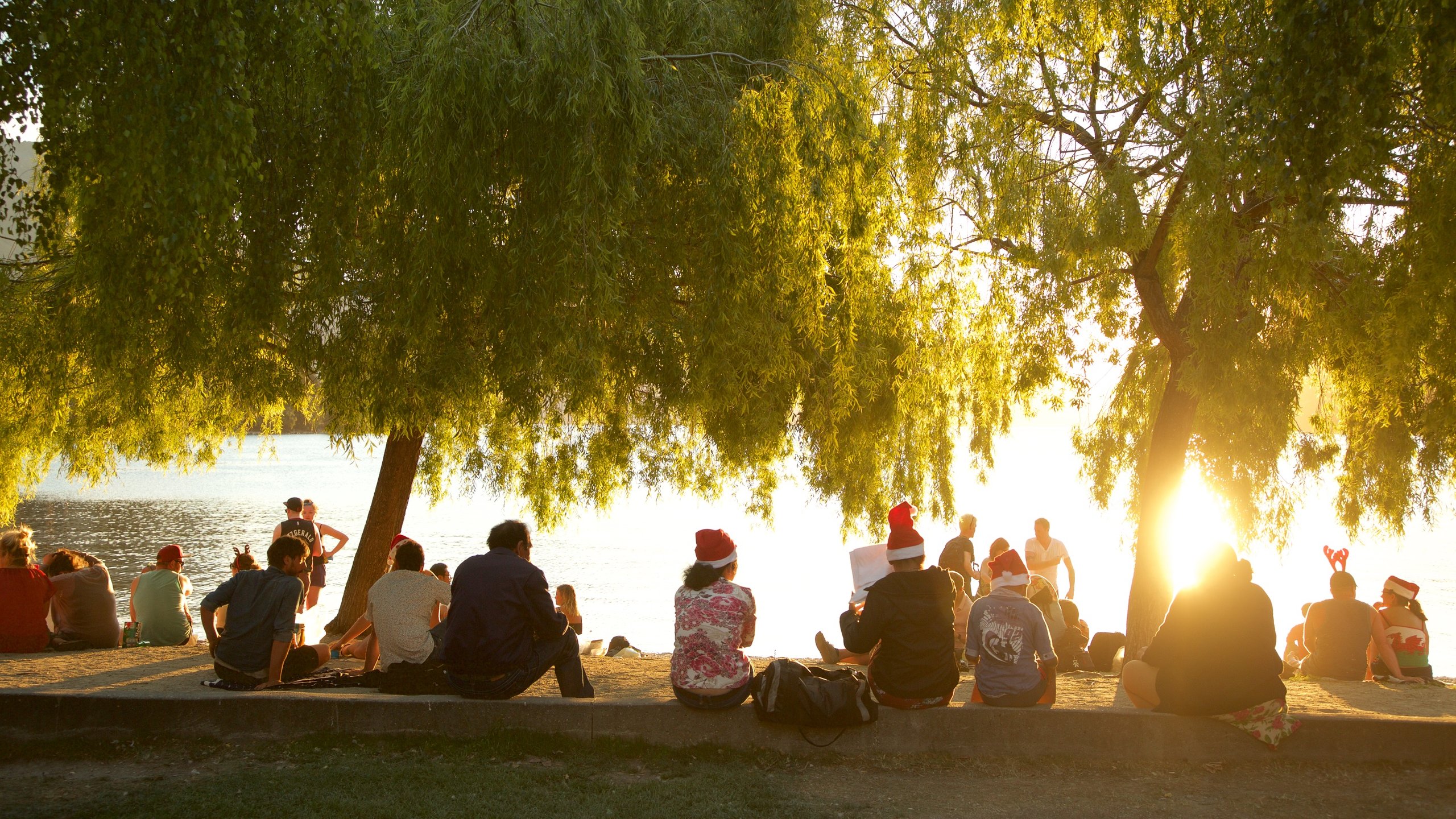 Queenstown City Centre featuring a sunset and a lake or waterhole as well as a large group of people