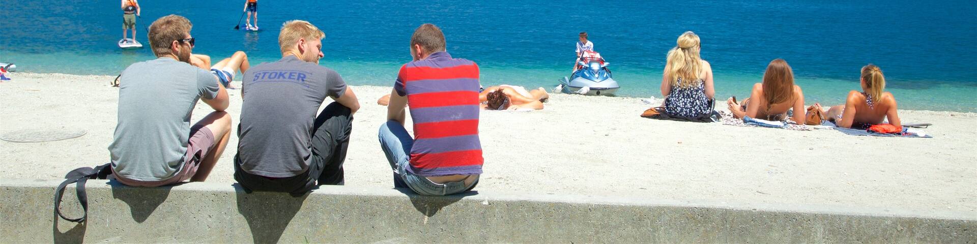 Queenstown City Centre showing general coastal views and a beach as well as a small group of people