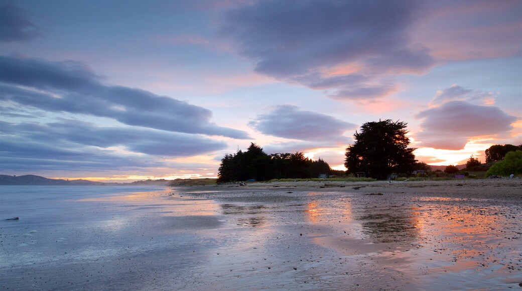 Oamaru que incluye una playa de arena, una bahía o puerto y una puesta de sol