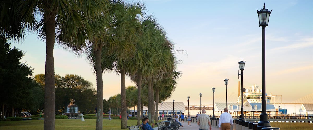 Charleston Waterfront Park showing a sunset and a park as well as a small group of people