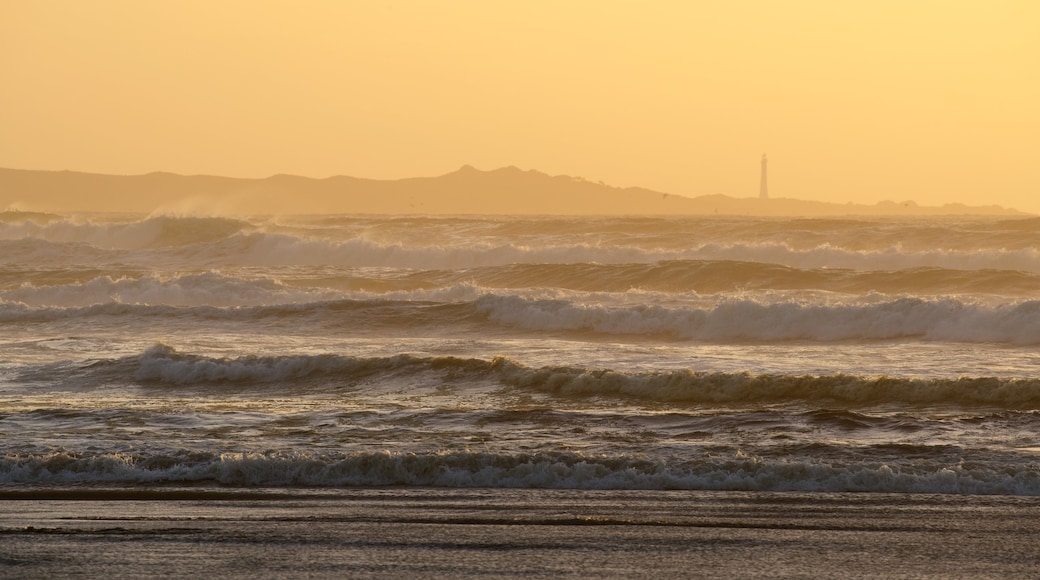 Strahan que incluye vista general a la costa, un atardecer y olas