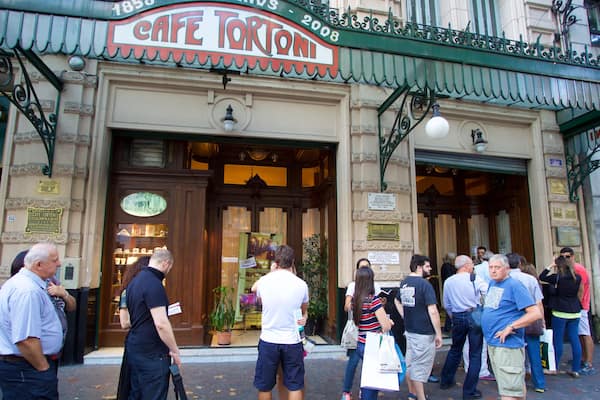 Cafe Tortoni montrant scĂšnes de rue et signalisation aussi bien que important groupe de personnes