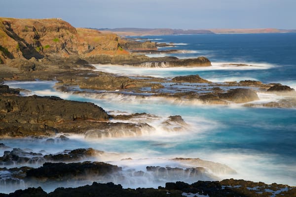 Phillip Island featuring a bay or harbour, rugged coastline and surf