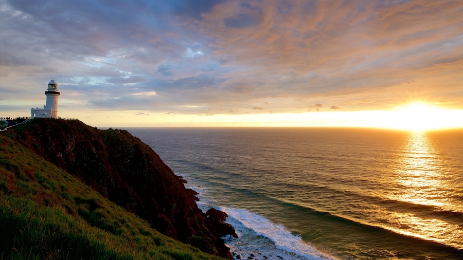 Cape Byron vuurtoren bevat een zonsondergang en rotsachtige kustlijn