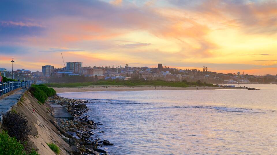 Newcastle featuring hiekkaranta, kaupungin liikealue ja auringonlasku
