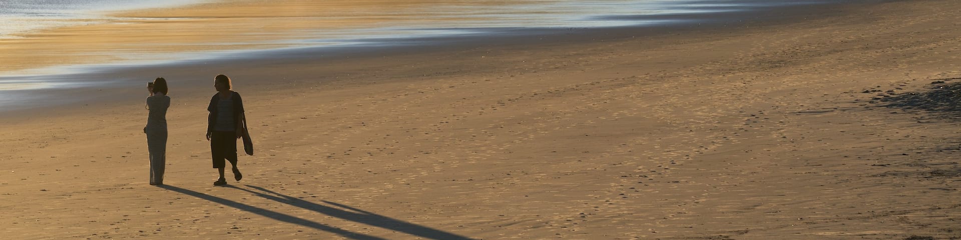 Main Beach featuring mist or fog and a sandy beach as well as a couple