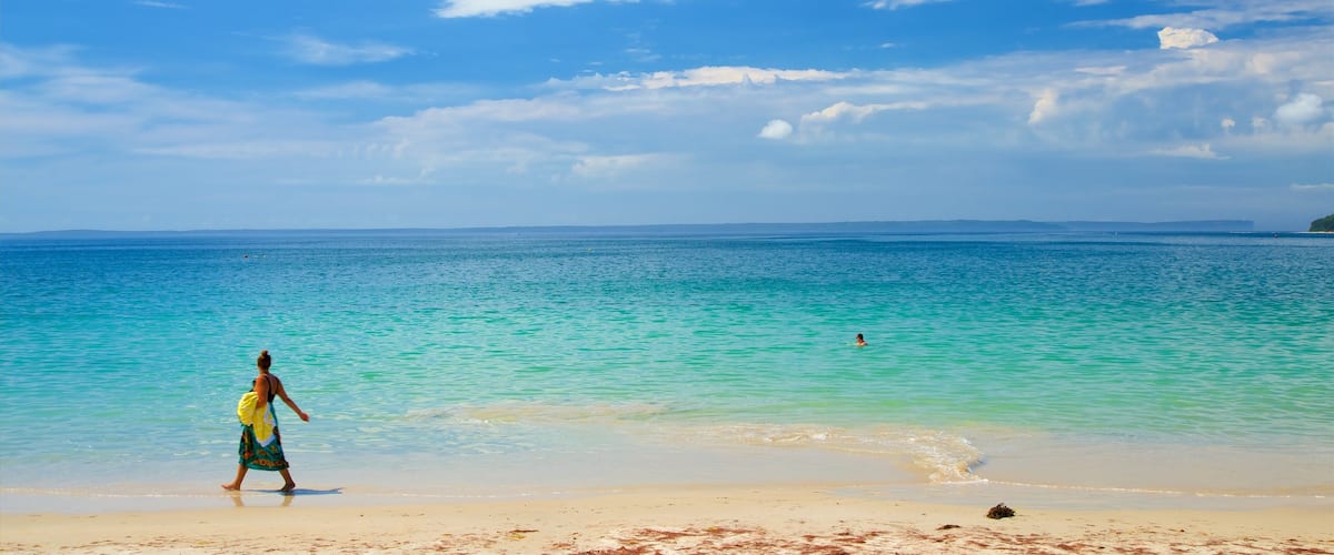 Collingwood Beach featuring a bay or harbour and a beach as well as a small group of people