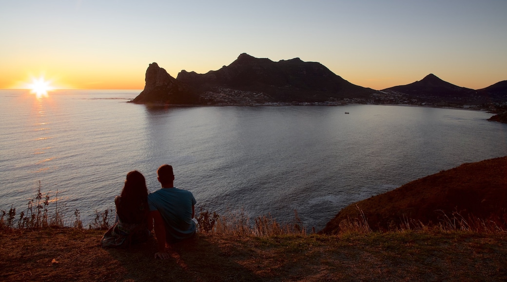 Chapmans Peak mostrando costa rocosa y un atardecer y también una pareja