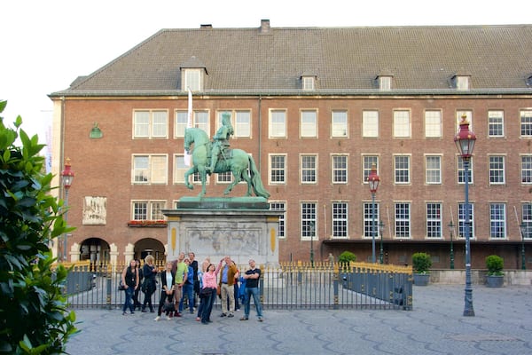 Marktplatz welches beinhaltet Statue oder Skulptur und Geschichtliches sowie kleine Menschengruppe