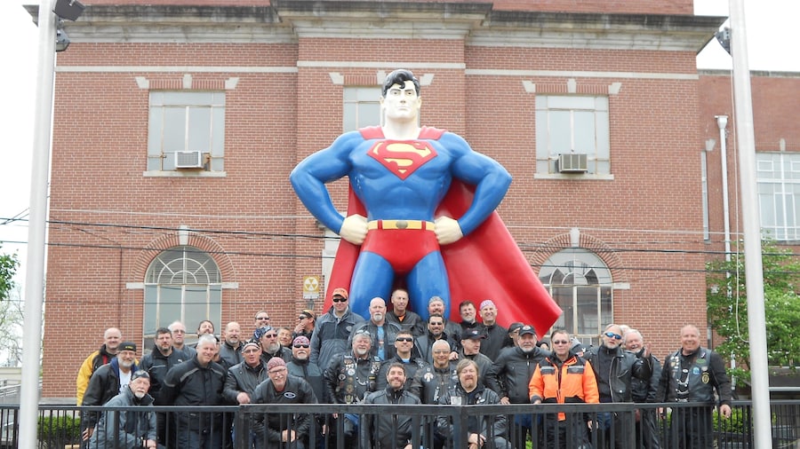 Superman Statue som inkluderar en staty eller skulptur såväl som en liten grupp av människor